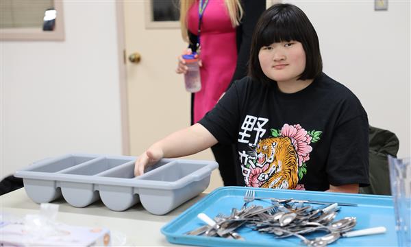 Girl smiles while sorting silverware